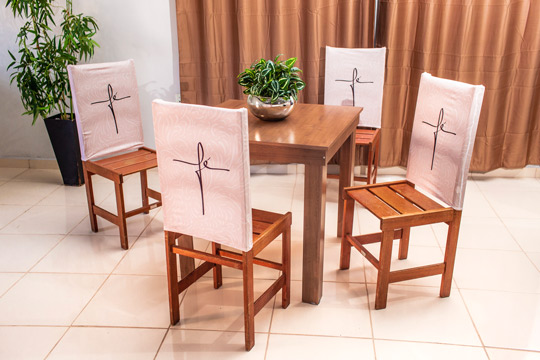 mesa de madeira com cadeiras cobertas com capas de encosto escrito fé