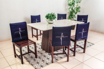 mesa de madeira com cadeiras cobertas com capas de encosto escrito fé