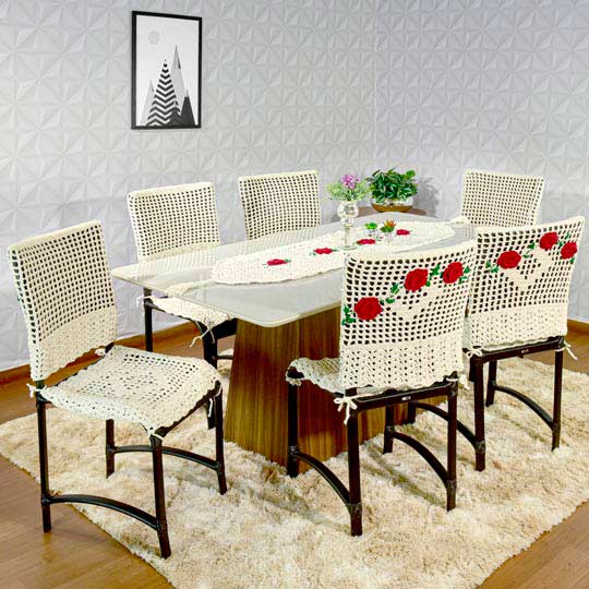 mesa de jantar com seis cadeiras com capas de crochê de linha crua com rosas nas costas 