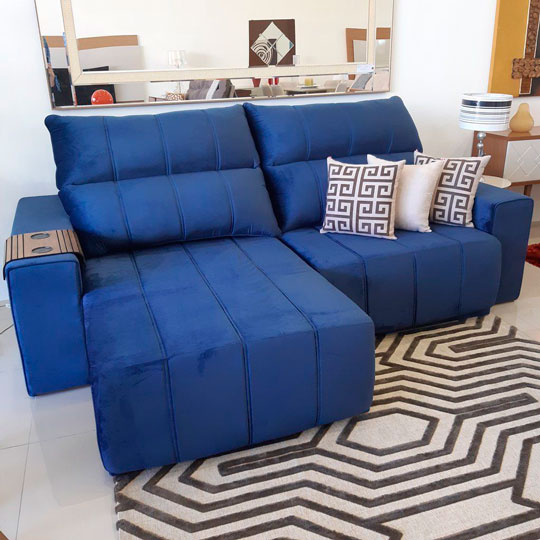 sofá retrátil azul com almofadas decorativas e tapete geométrico de cores neutras