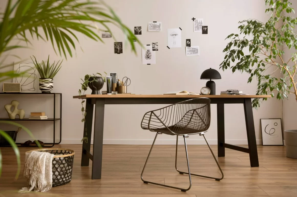 decoração home office elegante com mesa, cadeira, papéis colados na parede em um tom despojado, plantas e um espaço confortável