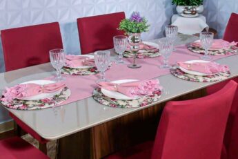 mesa de almoço com sousplats florais, trilho caminho de mesa rosa e guardanapos de tecido rosa rendado