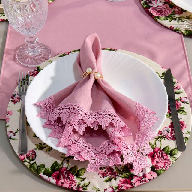 mesa posta para almoço com sousplat floral e guardanapo de tecido rosa rendado