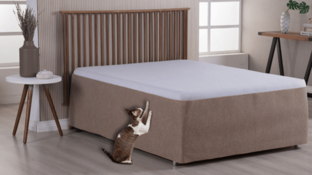 Gato arranhando protetor de cama box revestido com tecido resistente, em quarto com decoração moderna.