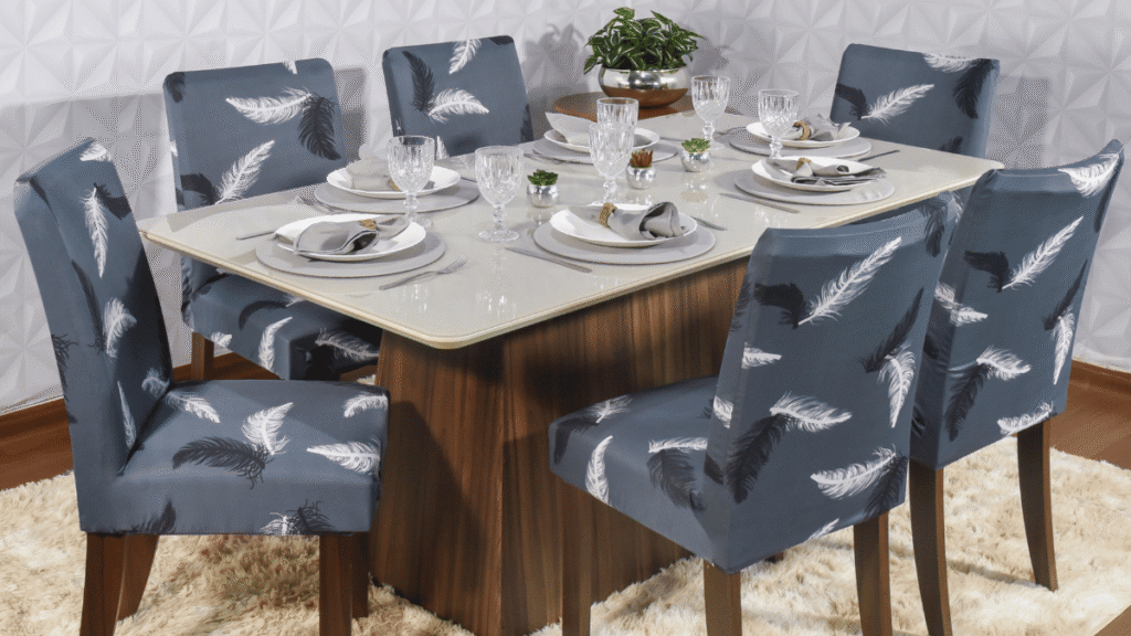 Capa para Cadeira de Jantar Modern Leaf – Estampa de penas brancas e pretas sobre fundo azul, em uma mesa posta com tons neutros.