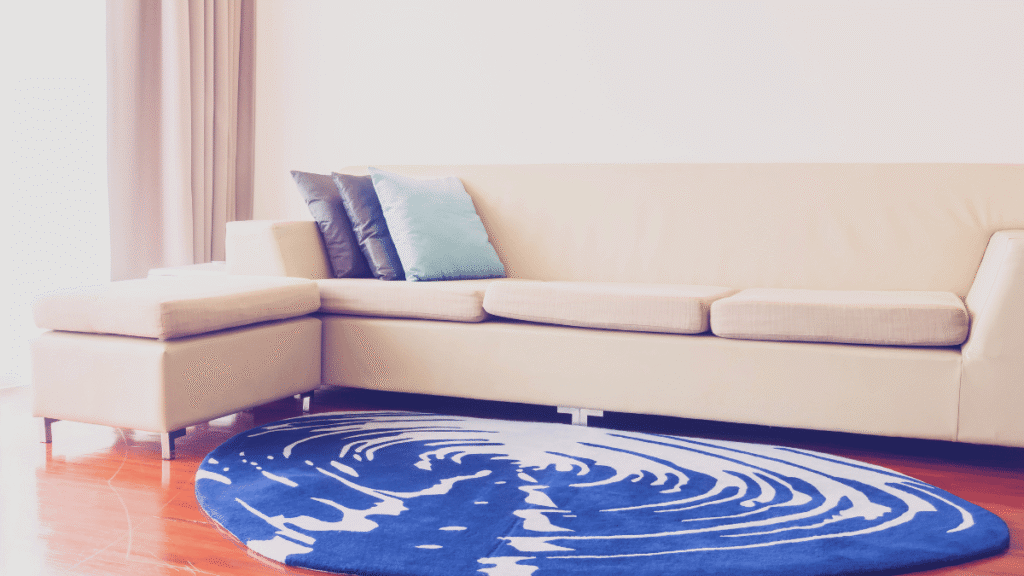 Sala com sofá bege e tapete redondo azul vibrante que destoa da paleta neutra do ambiente.